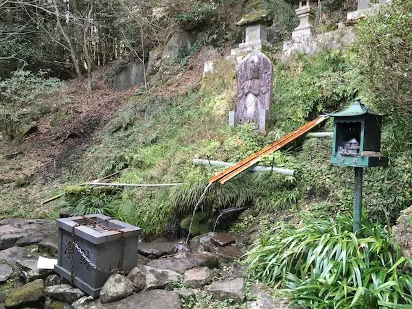 湧水の取水口全景と賽銭箱の写真